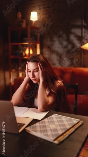 girl busy evening, woman working late at home, person stressed and focused on paperwork late at night, individual feeling overwhelmed while organizing documents and using laptop in quiet living space