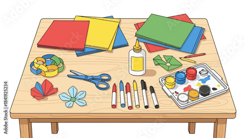 A wooden table is covered with art supplies, like paper, scissors, paint, and glue