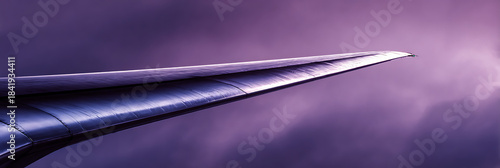 Sleek futuristic aircraft wing tip against a moody purple and blue sky, representing advanced aviation technology and modern travel.