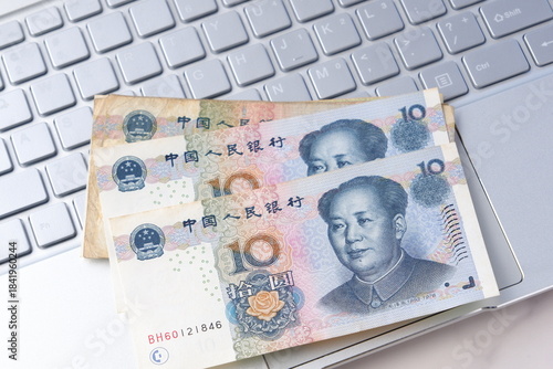 毛沢東の肖像が描かれた中国の通貨、人民元（RMB）の紙幣とノートパソコン
