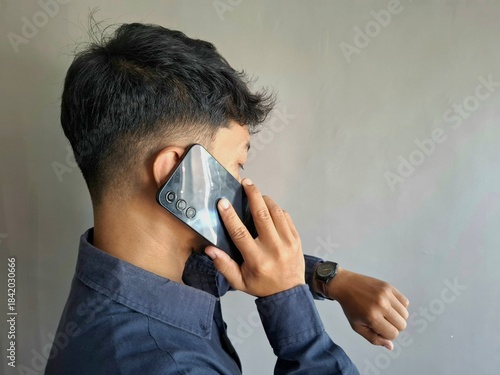 Close-up view of unrecognizable businessman holding phone to ear during serious conversation while checking time on wristwatch.