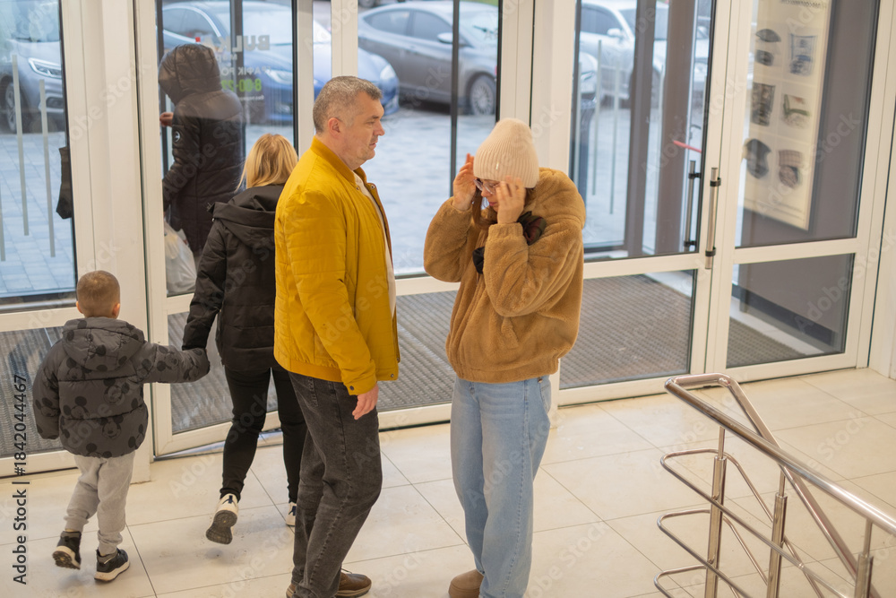 Obraz premium Visitors entering a building with a family stopping to talk in a lobby area during daytime