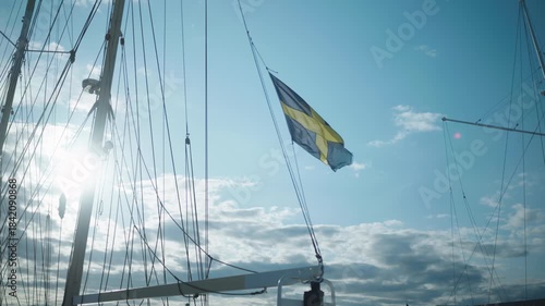 Wallpaper Mural Static slow-motion shot of a Swedish flag waving in the wind among sailboat masts, with bright sunlight and scattered clouds creating a crisp maritime atmosphere. Torontodigital.ca