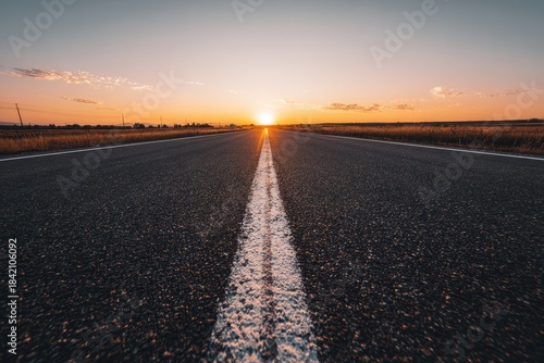 Serene empty road stretching into the horizon at sunrise, soft golden light illuminating the asphalt, symbolizing freedom and new beginnings
