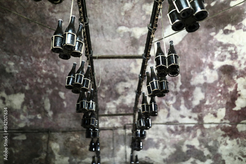 Many bottles hanging upside down on rack in cellar