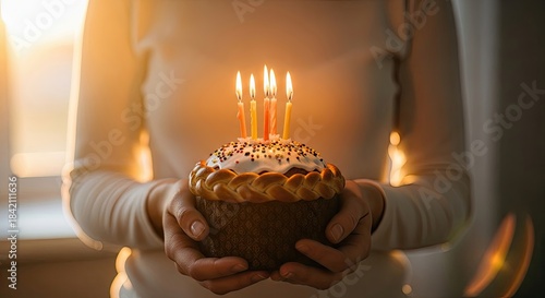 Hands holding traditional Easter cake with glowing candles, symbolizing hope