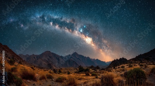 Vast milky way galaxy arches over rugged mountain landscape under starry night sky