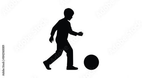 A young boy playfully kicking a soccer ball depicted in a striking black silhouette