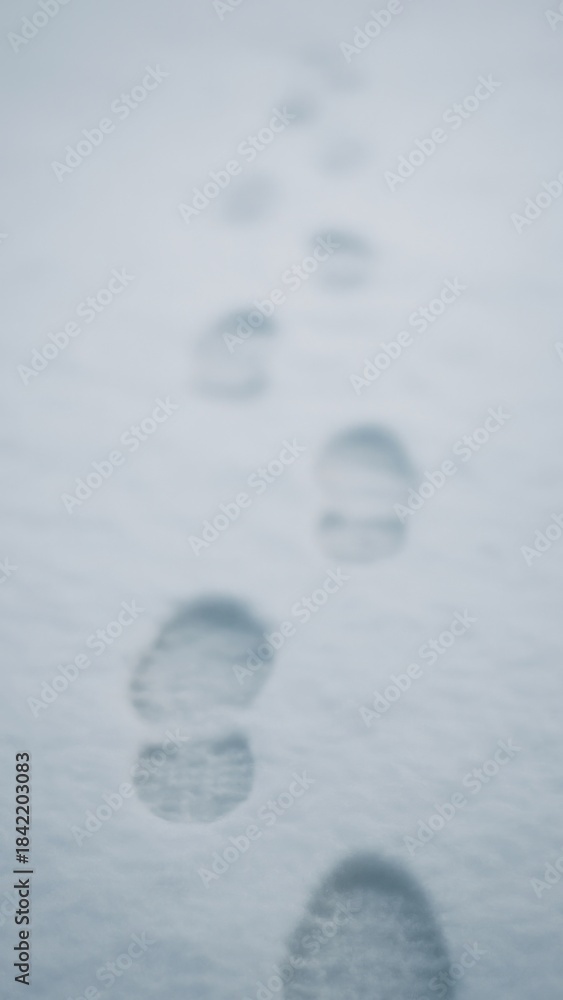 Naklejka premium Footprints trail across snowy landscape mobile wallpaper
