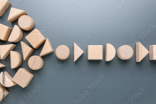 Scattered wooden geometric blocks gradually forming an organized single-line flow, symbolizing teamwork, alignment, system optimization, and the transformation from chaos to order in business process