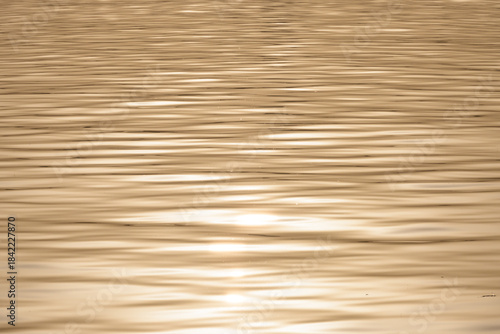 Golden water surface with rippling waves and light reflection