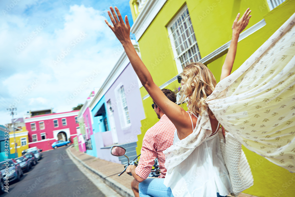Naklejka premium Arms raised, back and couple on scooter in city for holiday, travel or vacation together. Adventure, freedom and journey with excited people outdoor on moped for break or road trip in urban town