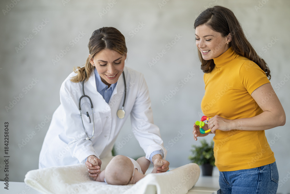 Obraz premium Pediatric check-up showing a doctor examining a baby while a mother observes in a warm clinic setting