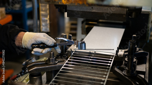 Bilde på lerret Close-up of factory worker hands operating metal stamping press with specialized