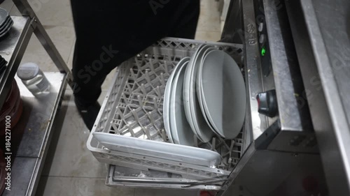 Restaurant worker loading plates into a commercial dishwasher
