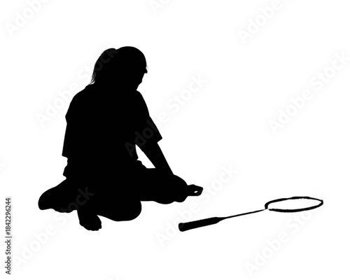 Silhouette of a person sitting next to a badminton racket on a