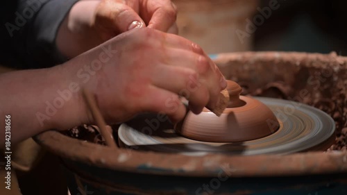 Potter trimming clay pot lid on pottery wheel close-up