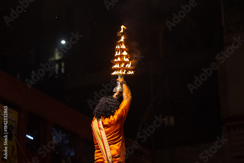 Ganga aarti, Portrait of an unidentified young male priest performing holy river ganga evening aarti at dashashwamedh ghat in traditional dress with hindu rituals.