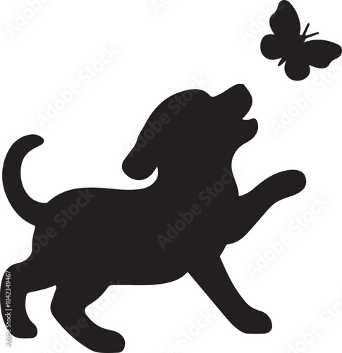 A playful puppy attempts to catch a butterfly in silhouette
