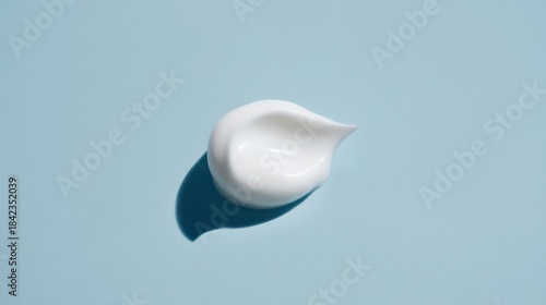 A small blob of white cream or cleanser on a light blue flat surface,