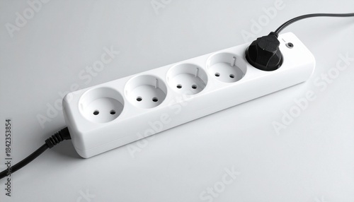 European-style white power strip with five round sockets, one occupied by black plug.