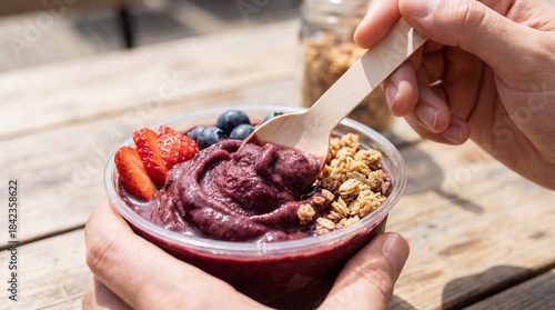 A hand-held acai bowl, offering a moment of healthy indulgence with a vibrant display of fruits and toppings.