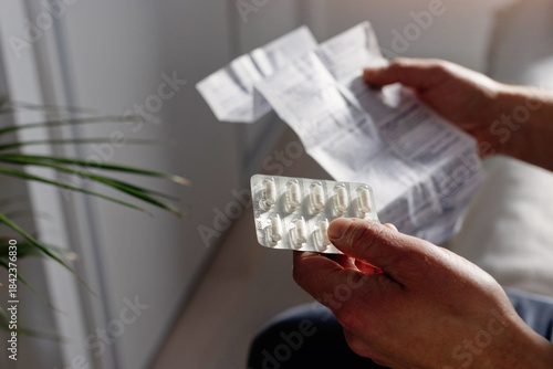 Tablou pe pânză Closeup of male hands holding pills package and reading medication instruction information about dosage and side effects, painkiller