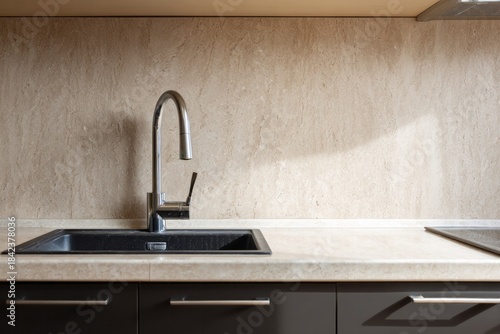 Modern kitchen sink with chrome faucet and textured backsplash.