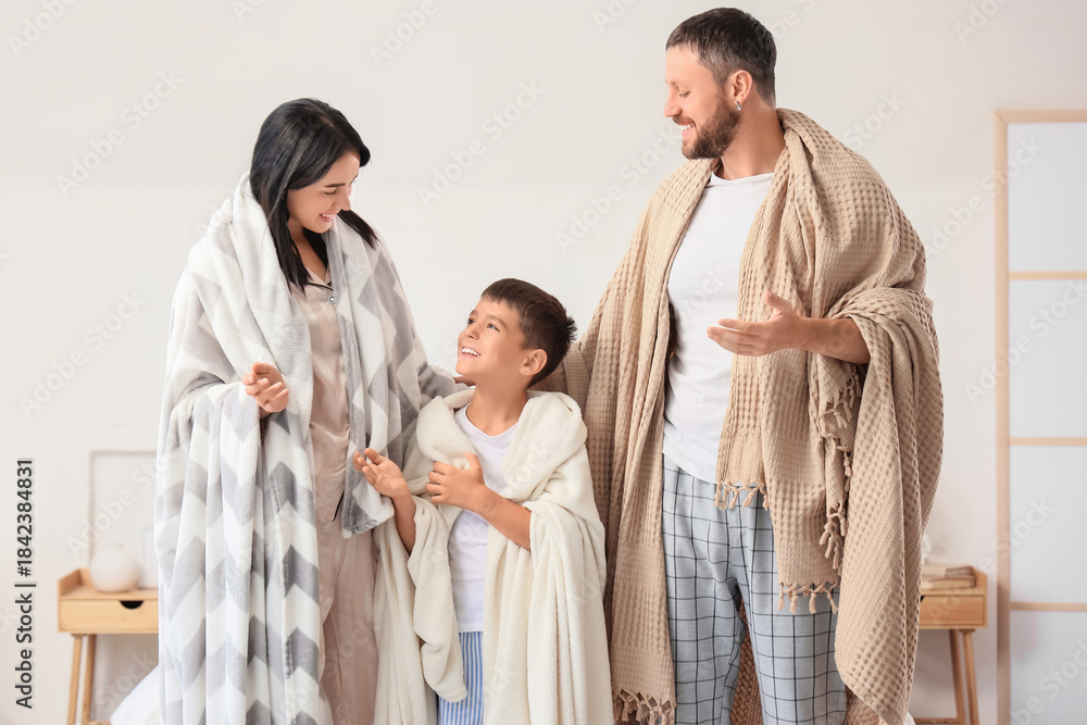 Obraz premium Happy parents and their little son with warm blankets in bedroom