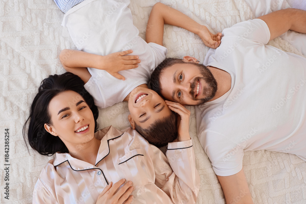 Obraz premium Happy parents and their little son lying on warm blanket, top view