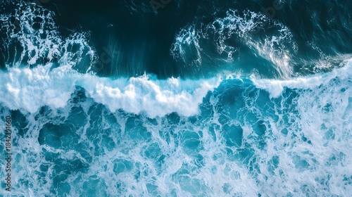 Fototapeta Naklejka Na Ścianę i Meble -  Top down aerial view of moody blue ocean wave with white foam