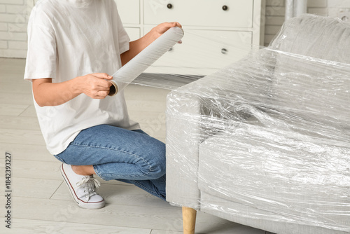 Young woman wrapping couch ...