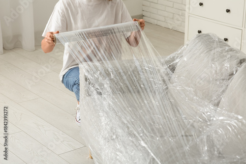 Young woman wrapping couch ...