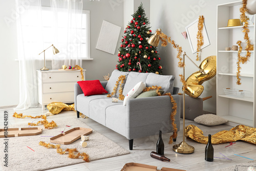Interior of messy living room with sofa and tinsel after New Year party