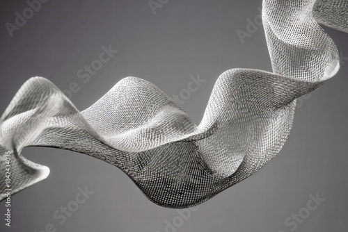 A textured fabric ribbon waves gracefully against a simple gray background, creating an image of flowing artistry and subtle monochrome elegance.