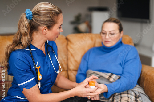 Nurse gives medication to patient in living room during home visit on a weekday