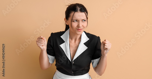 Tableau sur toile Angry young chambermaid on beige background