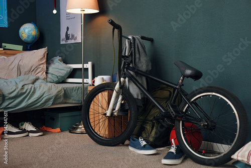 Wallpaper Mural Teenager bedroom showing stunt bicycle leaning against wall near unmade bed, sneakers on floor, backpack and globe in background, suggesting active lifestyle and youthful environment Torontodigital.ca