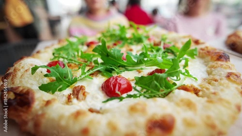 Two different pizzas are served on wooden plates at a busy food market