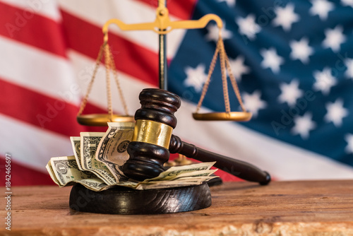 A judge's gavel on dollar bills with the scales of justice, the American flag in the background. Corruption and Unlawful Financial Influence in the United States Legal System. Bribery of the Judiciary