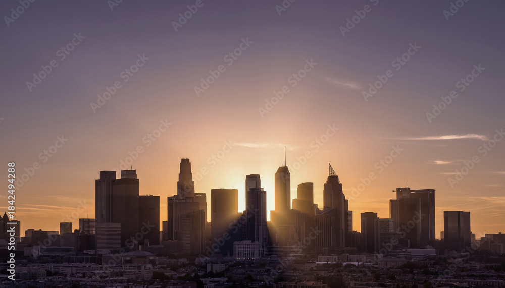 Obraz premium City skyline at sunset with silhouetted skyscrapers and a glowing horizon.