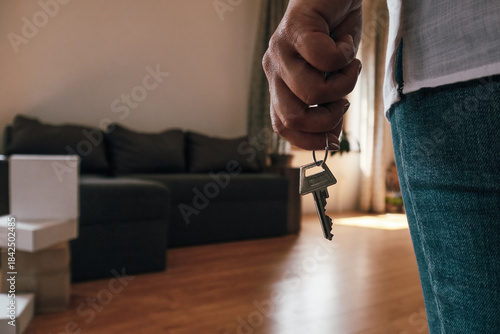 Person holding house keys in a new apartment living room.