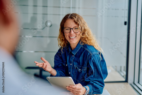 Fotografía Businesswoman engaging in a lively discussion, smiling and gesturing while holdi