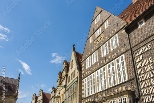 View of aged brick buildings reach for the clear blue sky, their gabled roofs and white-framed windows creating a timeless architectural tapestry, Bremen, Bremen, Germany.