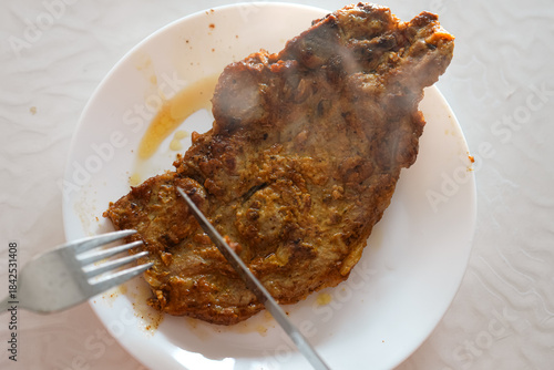 Cutting into steaming chop on porcelain plate reveals savory succulence