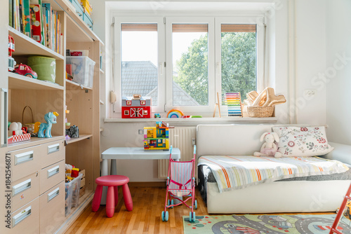 Tidy children room. Interior decor of clean children's room. Organizing storage in kids room: bookshelves and educational and soft toys. Montessori education. A childs bedroom with toys and books.