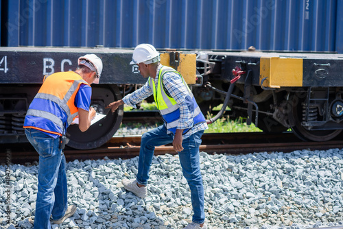 Foto Freight train engineers inspect a railcar wheel and axle, as two railroad worker