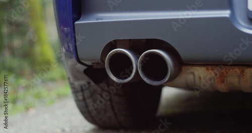 Generic car twin exhaust pipe tips track and pan shot  Low angle, close up shot, blurry nature background, dynamic real time video, no people