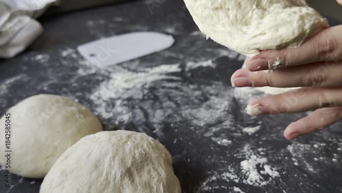 Female hands cutting and forming balls of fresh yeast dough on floured kitchen table