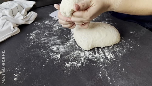 Female hands cutting and forming balls of fresh yeast dough on floured kitchen table